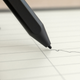 A close-up of the Kindle Scribe's Premium Pen stylus writing on the Scribe's screen.